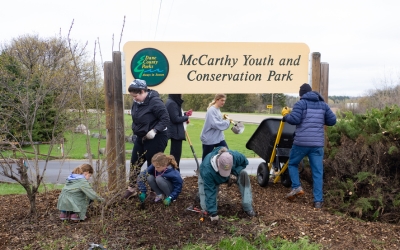 A group of volunteers cleaning up McCarthy Youth and Conservation Park's main sign. 