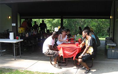 Large group eating at tables under the shelter