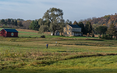 Person running on a grassy trail with historic buildings in the background.