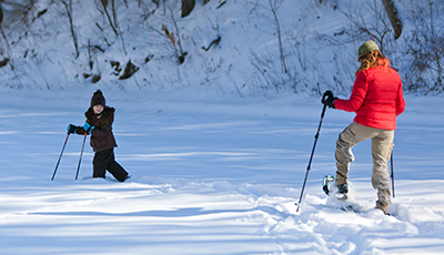 Adult and child snowshoeing through deep snow