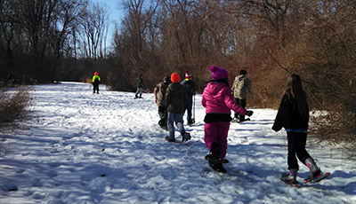 A group of children snowshoeing