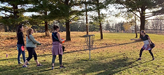 A group of people playing disc golf